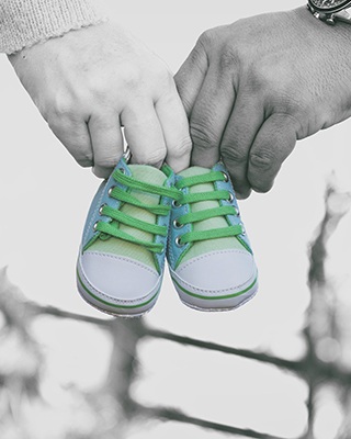 A couple holds a pair of baby shoes. This demonstrates concepts discussed in online pregnancy counseling in California with Headway Therapy.