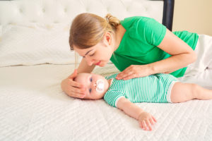 A woman smiles with her baby, no longer feeling symptoms of postpartum depression in San Diego, CA. She is feeling happy since starting postpartum therapy in California with Headway Therapy. 