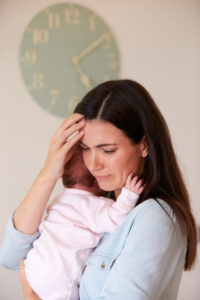 A mother holds her baby while crying. She is looking forward to beginning postpartum therapy in San Diego, CA with Headway Therapy. They have helped many women dealing with postpartum depression in San Diego, CA.