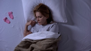 A woman lays in bed looking sad. She is waiting to begin miscarriage therapy in San Diego, CA. She also can chose online miscarrige therapy in California. 